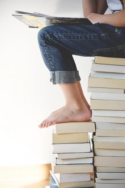 lower half of person sitting on a stack of books/Image by <a href="https://pixabay.com/users/pexels-2286921/?utm_source=link-attribution&amp;utm_medium=referral&amp;utm_campaign=image&amp;utm_content=1841116">Pexels</a> from <a href="https://pixabay.com//